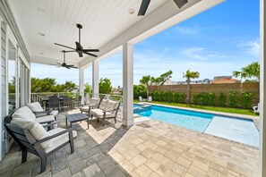 A covered patio with outdoor furniture, a pool, and a view of the surrounding landscape. - Tango Vista With Pool, Elevator, And Beach Views (Miramar Beach)