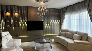 A modern living room with a sofa, a coffee table, a TV, and decorative wall panels. - Lüks villa (İstanbul)