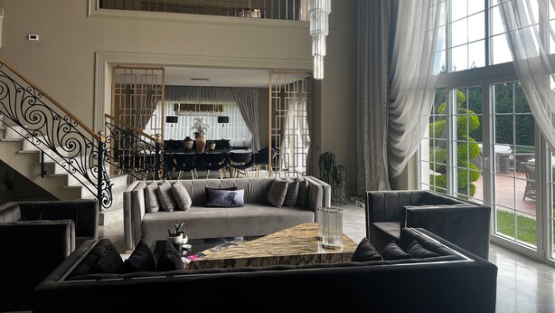 A spacious living room with a high ceiling, a staircase, and a dining area. - Lüks villa (İstanbul)