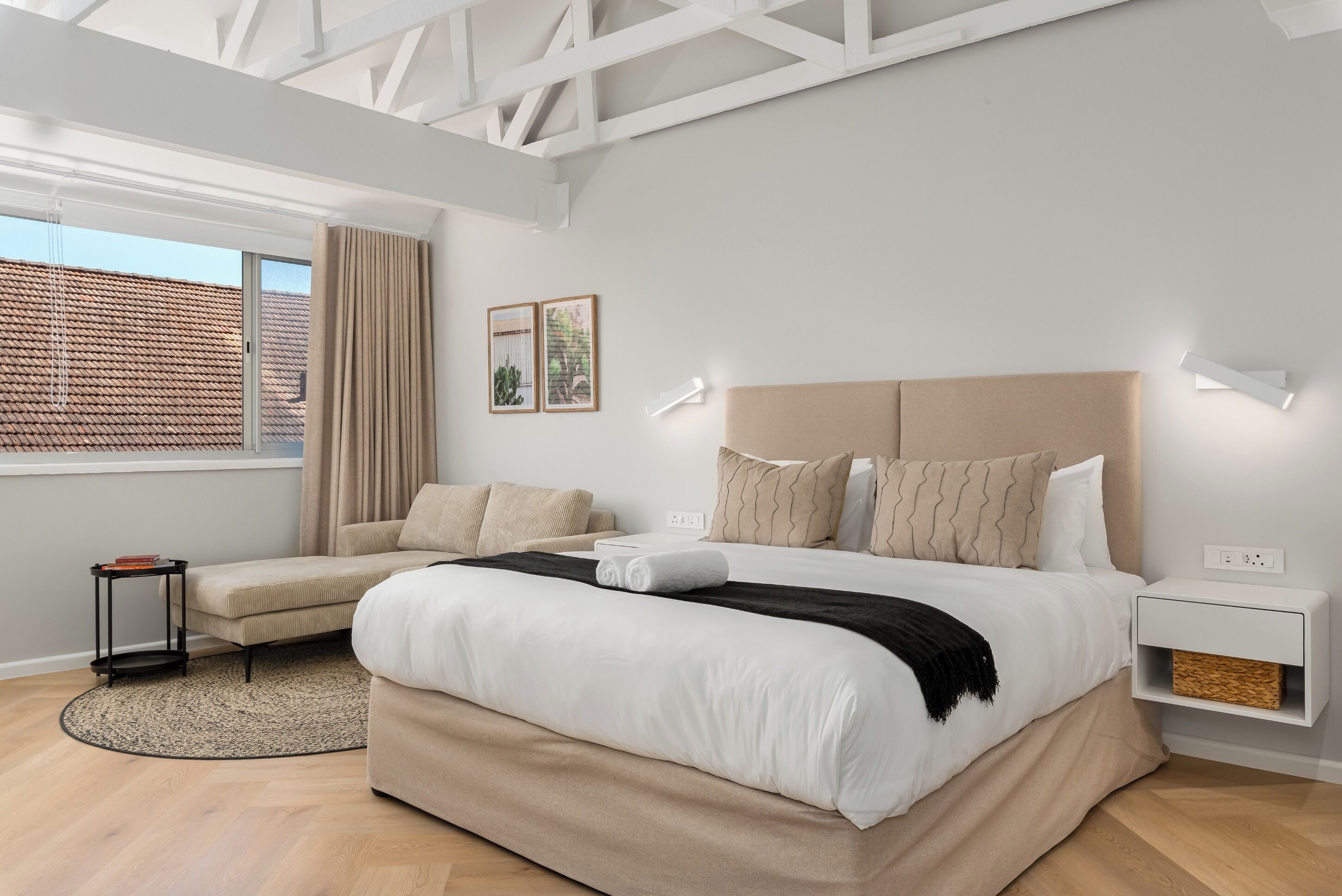 Ein modernes Schlafzimmer mit einem großen Bett, einer Couch, einem kleinen Tisch und einem Nachttisch.