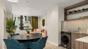Een functionele woonruimte met een eethoek, een bank, een wasmachine en een kitchenette.