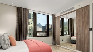 Een moderne hotelkamer met een groot bed, uitzicht op de stad en een schuifdeurkast.