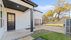 Ein modernes Haus mit überdachter Veranda, Garage und gepflegtem Rasen.