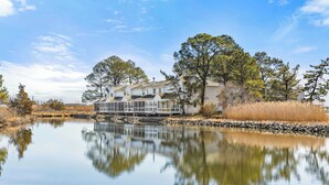 A lakeside property with a large house featuring a covered porch and multiple windows. - NEWLY RENOVATED - Mallard Lakes - Rare 3 bedroom unit near Fenwick & OC. (Selbyville)