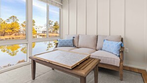 A cozy room with a large window, a sofa, and a wooden table. - NEWLY RENOVATED - Mallard Lakes - Rare 3 bedroom unit near Fenwick & OC. (Selbyville)