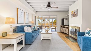 A modern living room with a blue sofa, white coffee table, and a fireplace. - NEWLY RENOVATED - Mallard Lakes - Rare 3 bedroom unit near Fenwick & OC. (Selbyville)