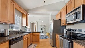 A modern kitchen with wooden cabinets, stainless steel appliances, and a granite countertop. - Waterview 3 bed in Sunridge Woods (Davenport)