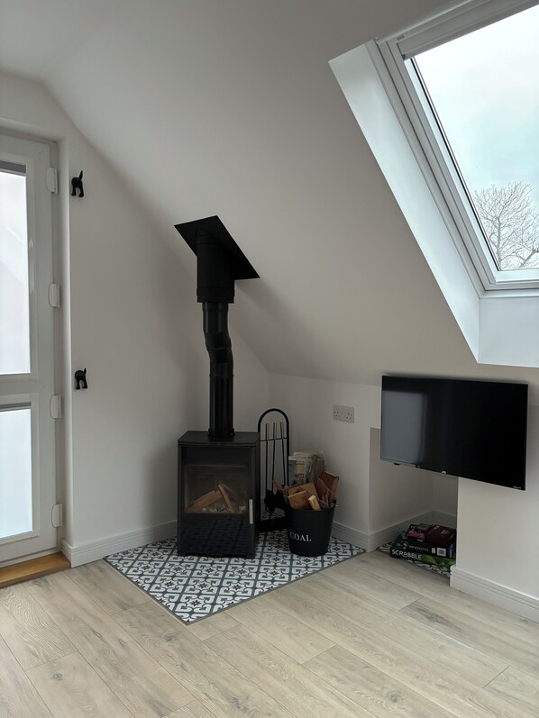 A room with a black wood-burning stove, a patterned rug, and a television mounted on the wall.