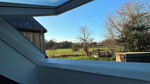A skylight with a view of a rural landscape, including fields and trees.