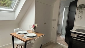 A modern kitchen with a dining area, featuring a skylight, a black oven, and a wooden dining table with chairs.
