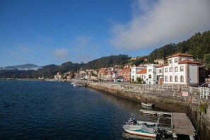 Traditional buildings line the serene waterfront, offering stunning views of the surrounding hills and boats docked along the shore.
