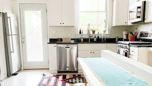 A modern kitchen with white cabinets, a stainless steel refrigerator, a dishwasher, and a large island with stools. - Peaceful Living-2Bdrm/2Bath w/Private Parking, WiFi-Work Station-Wicker Park! (Chicago)