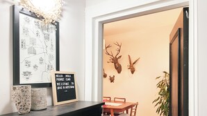 A dining area with a wooden table and chairs, a blackboard with a welcome message, decorative deer heads on the wall, and a framed map on the wall. - Peaceful Living-2Bdrm/2Bath w/Private Parking, WiFi-Work Station-Wicker Park! (Chicago)