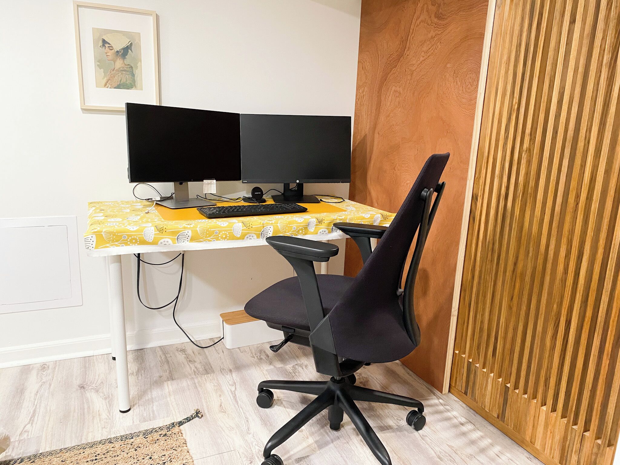 A workspace with two monitors, a keyboard, and a black office chair.