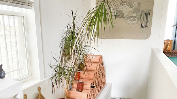 A staircase with potted plants and baskets, a bed in the adjacent room, and a wall with a decorative sketch. - Peaceful Living-2Bdrm/2Bath w/Private Parking, WiFi-Work Station-Wicker Park! (Chicago)