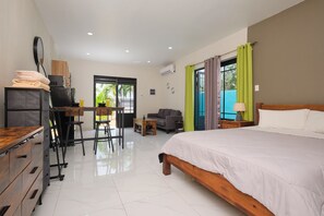 A hotel room with a bed, a desk with a chair, a sofa, a small table, and a wardrobe.