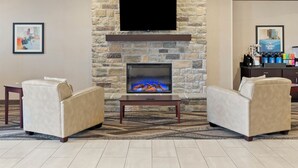 A hotel lobby with a stone fireplace, two sofas, a flat-screen TV, and a coffee station. - Cobblestone Hotel & Suites - Ephraim (Ephraim)