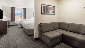 A hotel room with a large bed, a sofa, a desk with a chair, a TV, and a window with curtains. - Cobblestone Hotel & Suites - Ephraim (Ephraim)