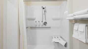 Un box de ducha moderno con puerta de vidrio, un perchero con toallas dobladas y un estante con artículos de aseo.