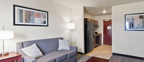 A living room with a grey sofa, a wooden coffee table, a lamp, and a framed abstract painting on the wall.