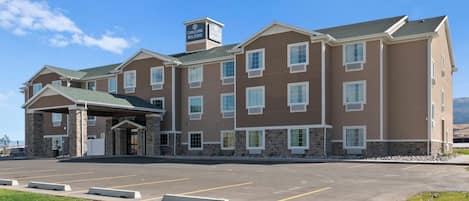 A hotel with a covered entrance, multiple floors, and a parking lot.