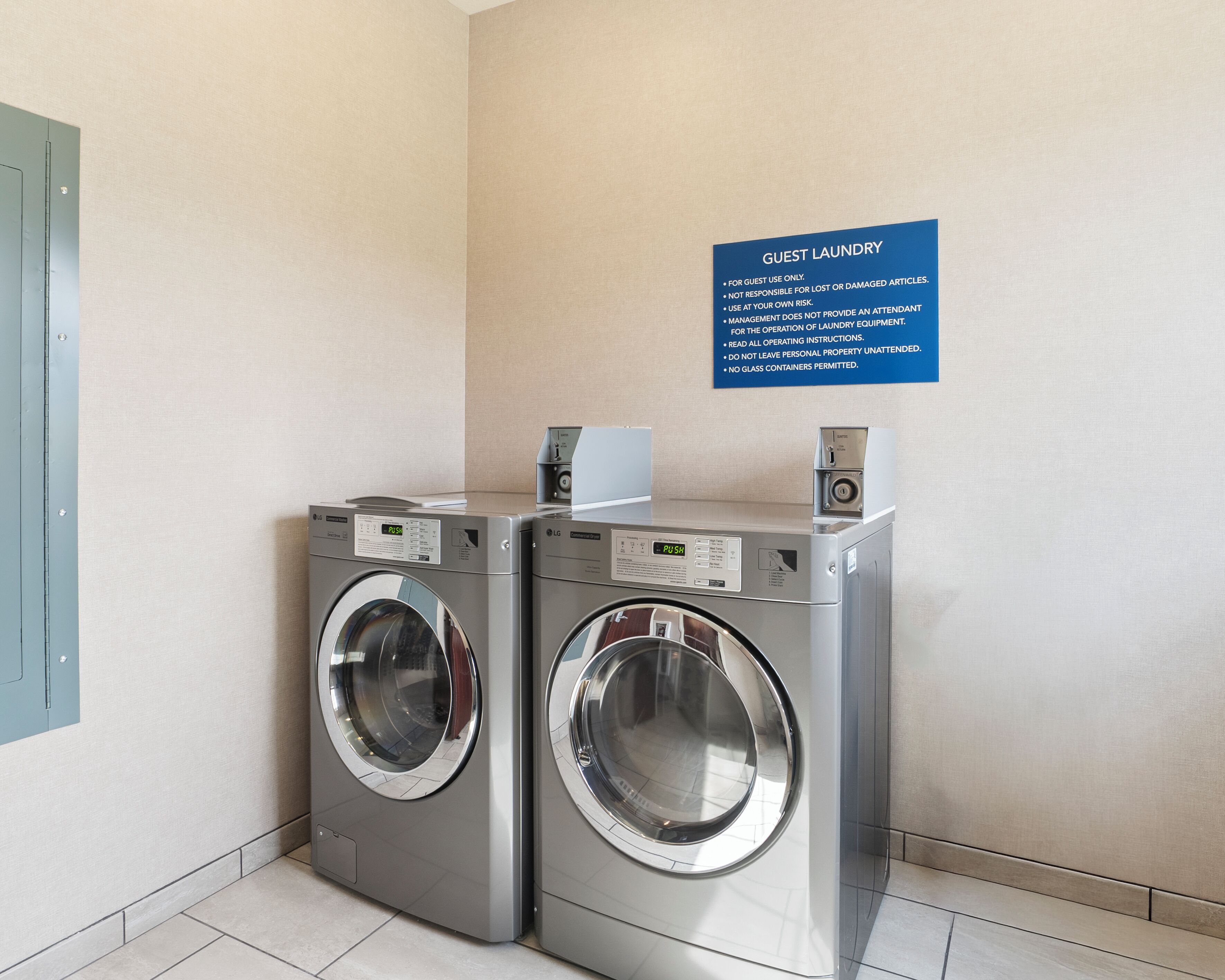 A laundry area with two LG commercial-grade washing machines and a blue sign with guest laundry instructions.