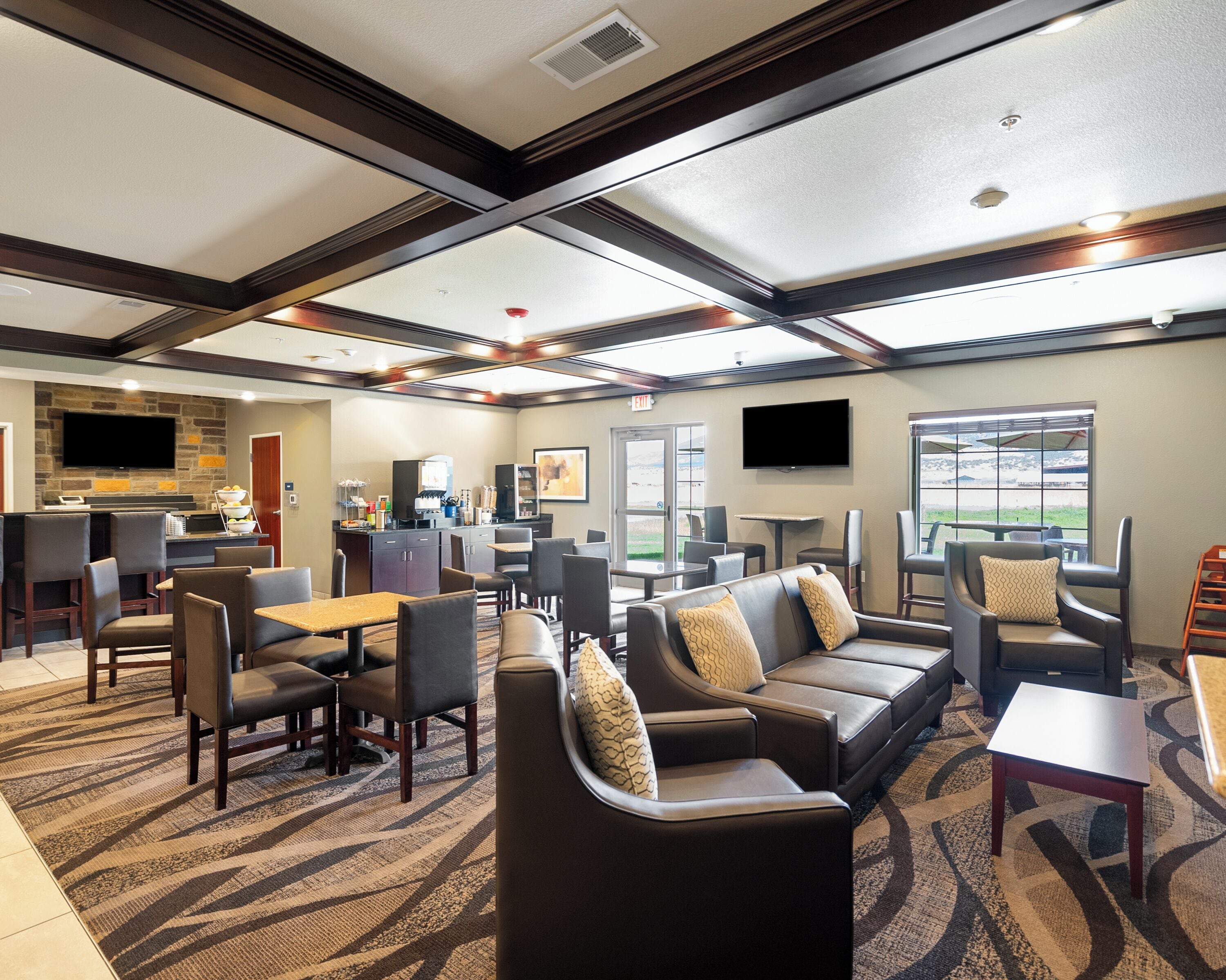 A hotel lobby with a seating area, a kitchen, and a large window offering a view.