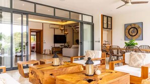 Un'ampia zona giorno con una grande vetrata che dà su un balcone, arredi in legno e un design d'interni moderno.
