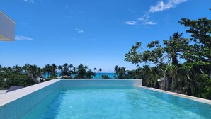 Una piscina cristallina con vista sull'oceano e palme.