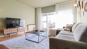 Ein Wohnzimmer mit Fernseher, Sofa, Couchtisch und Blick ins Freie.