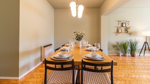 Een eetkamer met een houten tafel gedekt voor zes personen, omringd door stoelen met geweven zittingen.