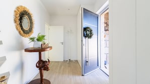 A hallway with a round wooden table, a mirror, and a welcome sign. - GIL LOVE - Luxurious V5 w/ Pool by LovelyStay (Vila Nova de Gaia)