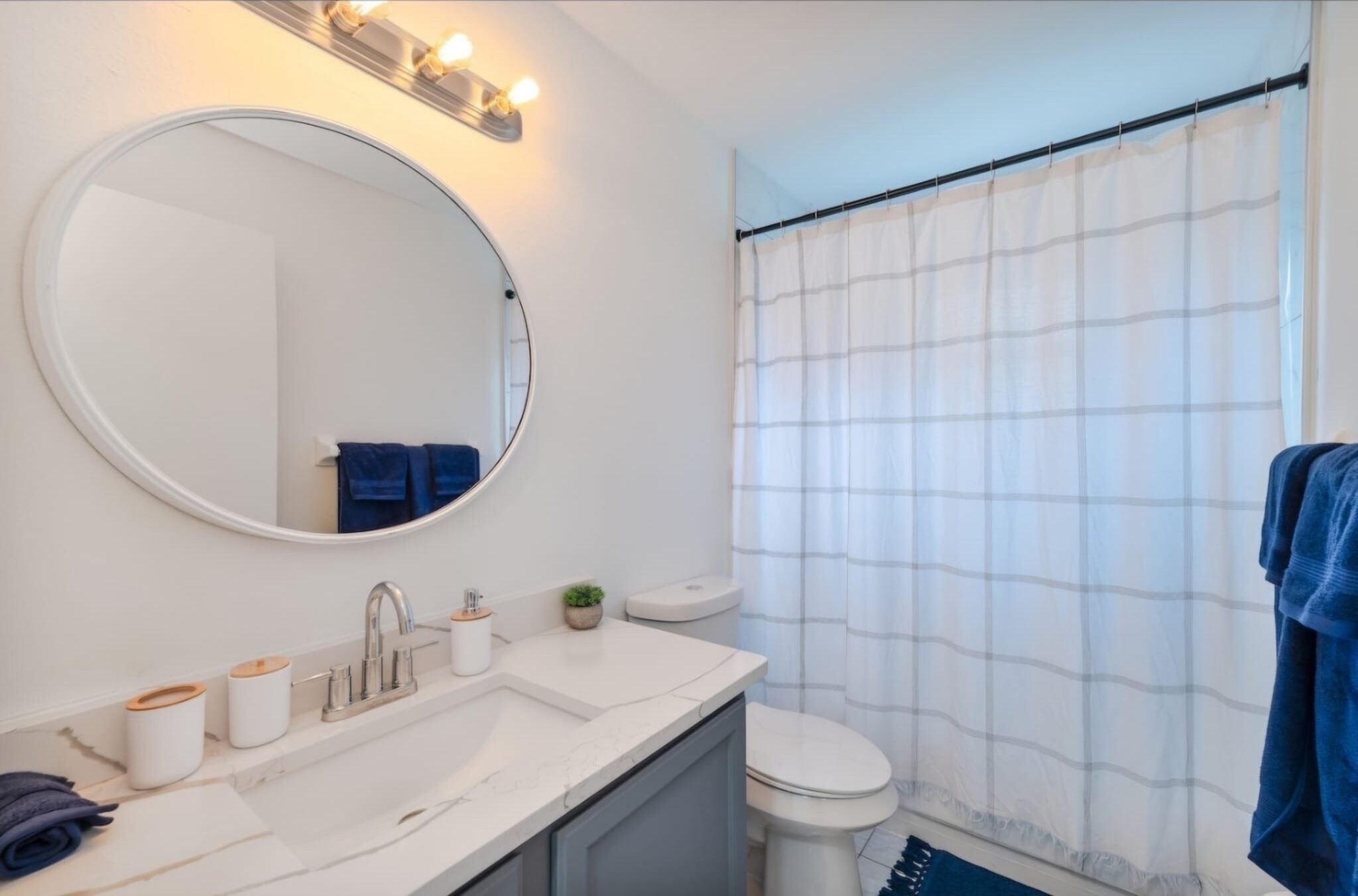 A bathroom with a round mirror, white sink, and a toilet.