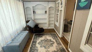 Una habitación con un sofá gris, un tapete estampado y estanterías empotradas con libros.
