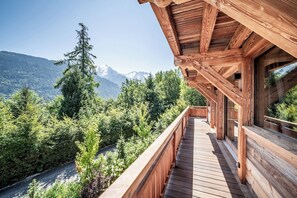 A wooden balcony with a view of a forest and mountains.