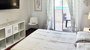 Una habitación de hotel con cama, escritorio, silla, televisor y vistas al exterior.