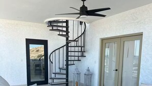 A modern living room with a spiral staircase, a ceiling fan, and a sliding glass door. - Luxury Villa w/Ocean views, Private Pool & Hot Tub. Steps from the beach! (San Felipe)