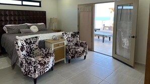 A bedroom with a bed, two chairs, a nightstand, and a sliding glass door leading to a balcony. - Luxury Villa w/Ocean views, Private Pool & Hot Tub. Steps from the beach! (San Felipe)
