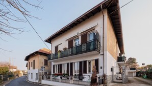 Un immeuble de deux étages doté d’un balcon, d’une entrée fermée par un portail et surplombant un ciel dégagé.