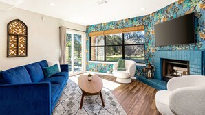 Ein modernes Wohnzimmer mit einem blauen Sofa, einem weißen Sessel und einem Kamin.