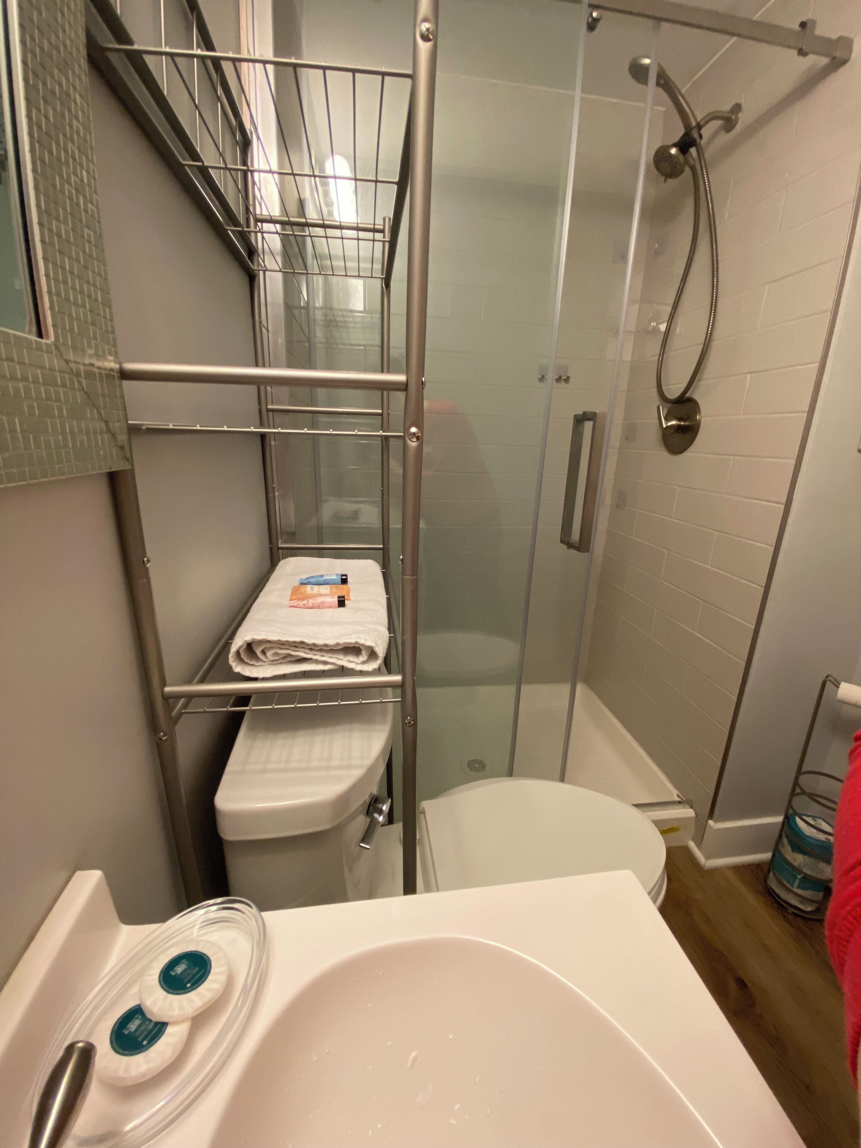 Ein Badezimmer mit einer Duschkabine, einer weißen Toilette und einem Waschbecken mit Seifenspendern.