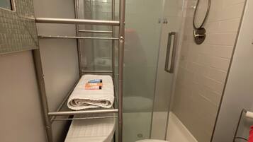 Ein Badezimmer mit einer Duschkabine, einer weißen Toilette und einem Waschbecken mit Seifenspendern.