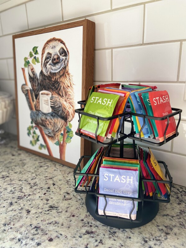 Estación de café con ilustración de perezoso y bolsas de té etiquetadas.