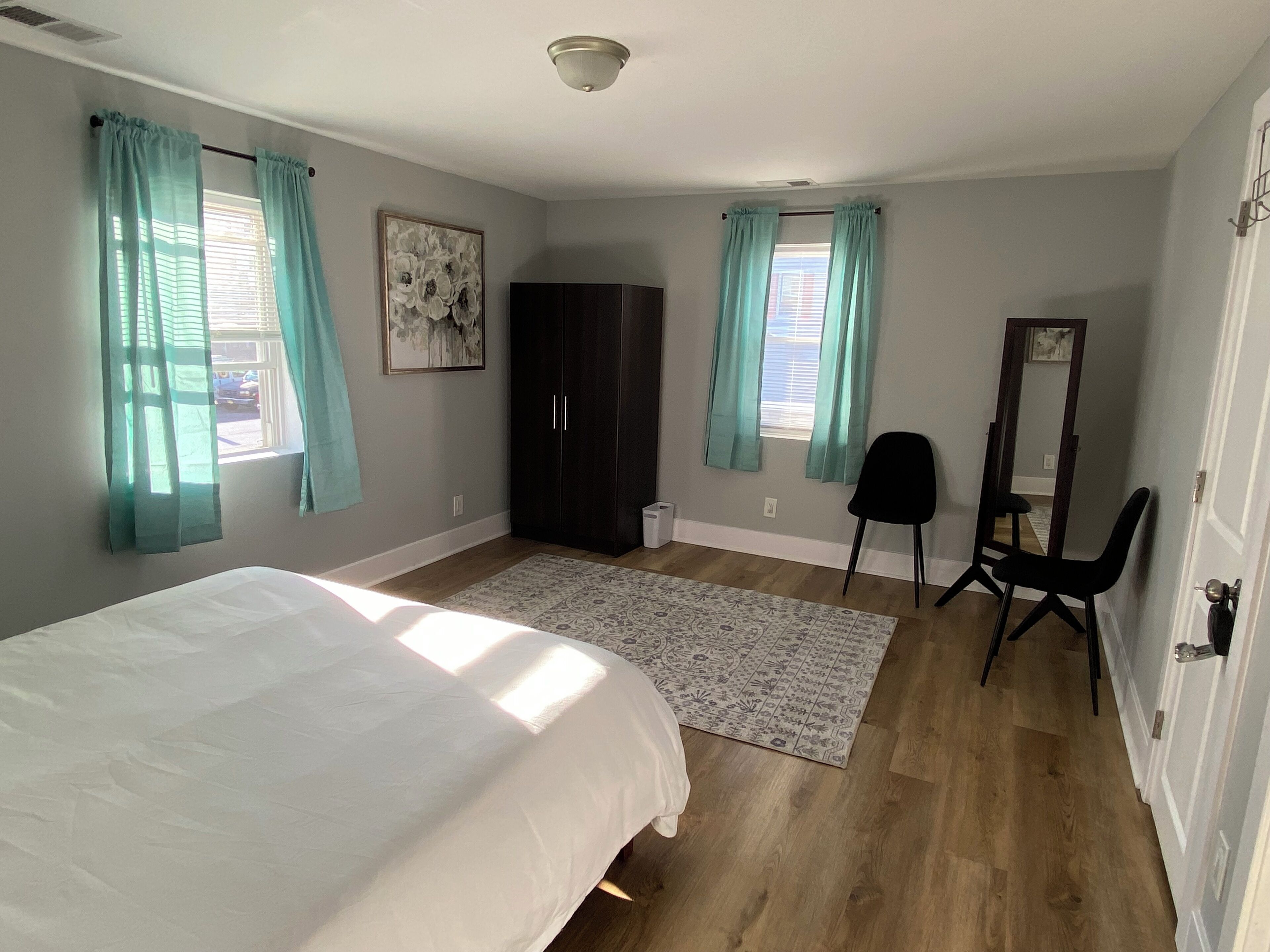 Une chambre à coucher avec un lit, une armoire, une chaise, un miroir et un tapis.