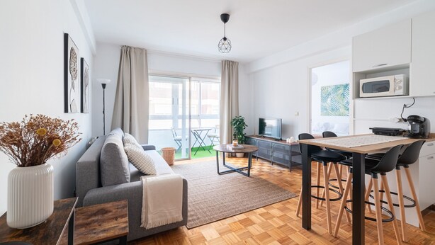 Una sala moderna con un sofá, una mesa de comedor y una zona de cocina con un microondas.
