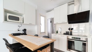 Una cocina moderna con microondas, refrigerador, horno y una mesa de comedor con sillas.