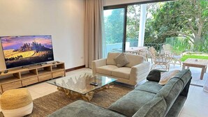 Una sala de estar moderna con un sofá, una mesa de centro de vidrio y una televisión.
