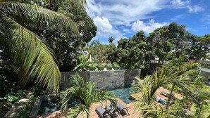 Zona de piscina con sillas de descanso y una pared de piedra.