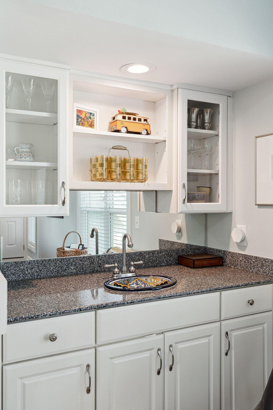A kitchen with white cabinetry, a granite countertop, and a built-in sink.