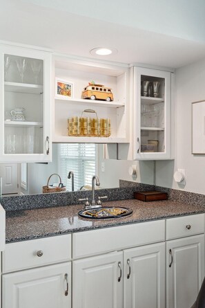 A kitchen with white cabinetry, a granite countertop, and a built-in sink.